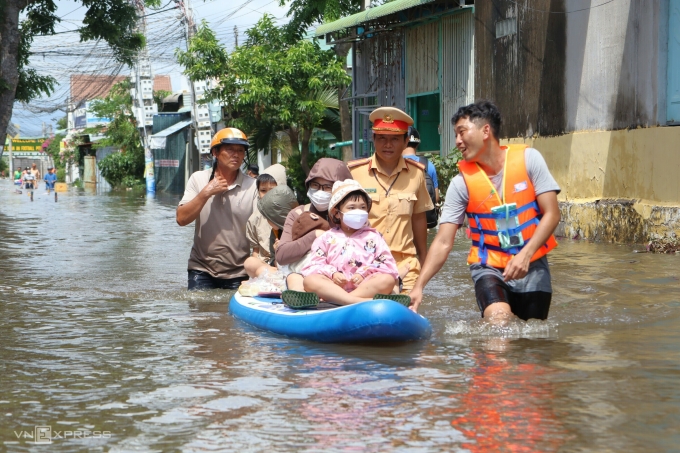 Gia đình chị Nguyễn Hà My (khu Bến Lội) cùng con nhỏ được lực lượng chức năng chuyển ra ngoài vùng ngập bằng thuyền sup, trưa nay. Ảnh: Việt Quốc