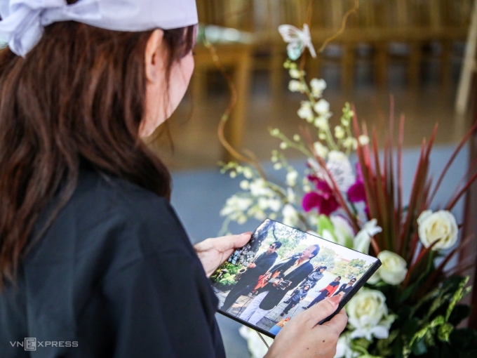 Con gái nhạc sĩ Thế Hiển xem lại các bức hình của bố ở lễ tang. Ảnh: Phùng Tiên