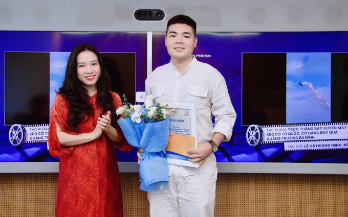 Bà Nguyễn Thu Hương - Phó tổng Biên tập Báo VnExpress - trao giải nhì cho anh Lê Hà Hoàng Minh, đồng tác giả tác phẩm Trực thăng bay xuyên mây kéo cờ Tổ quốc, cờ Đảng bay qua quảng trường Ba Đình. Ảnh: Duy Anh
