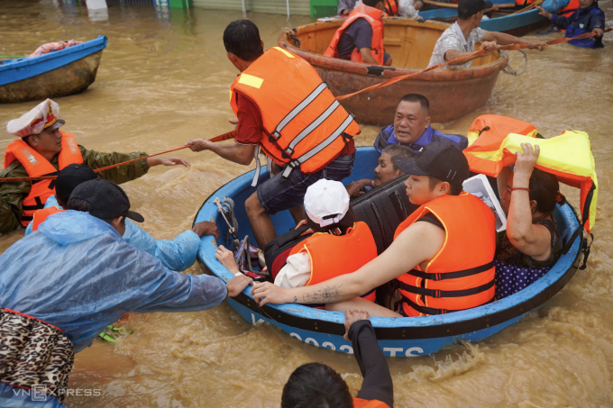Các đội cứu hộ phường Tây Nha Trang dùng thuyền thúng chở người, tài sản đến nơi an toàn. Nước lũ chảy xiết trên đường khiến việc cứu hộ gặp khó khăn. Ảnh: Bùi Toàn