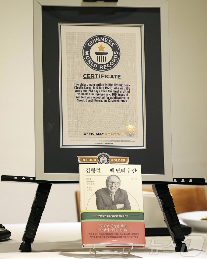 Giấy chứng nhận kỷ lục Guinness và quyển sách mới của ông được trưng bày tại buổi họp báo. Ảnh: News1