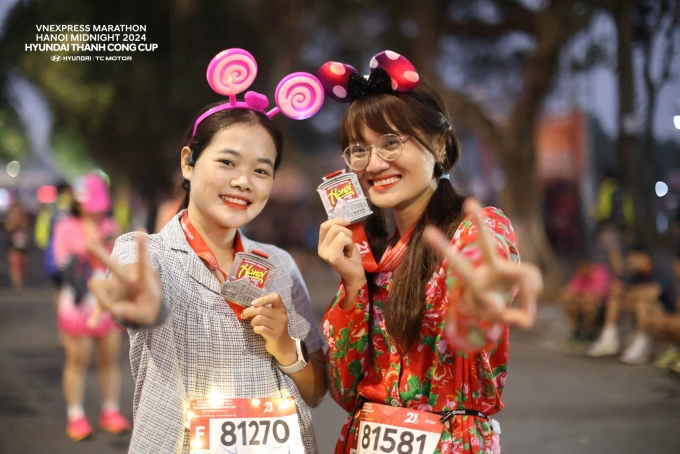 Hai nữ runner tươi cười khi check-in cùng huy chương VnExpress Marathon Hà Nội Midnight 2024. Ảnh: VnExpress Marathon