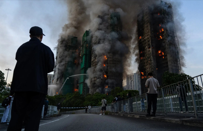 Người dân đứng từ xa nhìn ngọn lửa bao chùm các tòa nhà trong khu chung cư Wang Fuk Court thuộc quận Tai Po, Hong Kong, hôm 26/11. Ảnh: Chan Long Hei/Associated Press