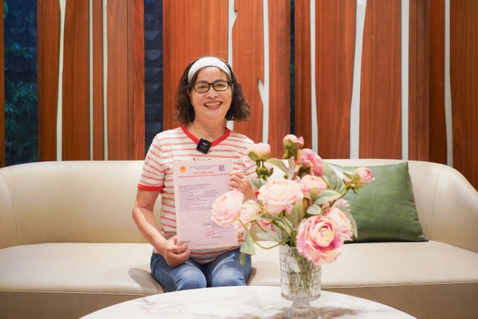 Bà Hoàng Thị Nhi nhận sổ hồng. Ảnh: Novaland
