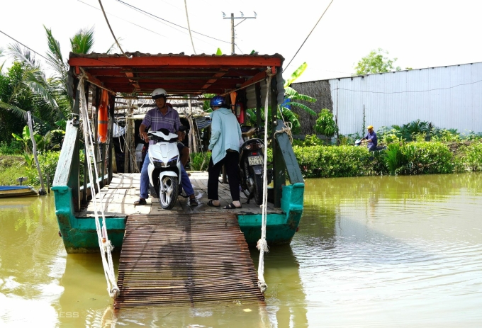 Người dân qua phà tại kênh Bà Phương khi cầu đang đổ móng. Ảnh: Chúc Ly