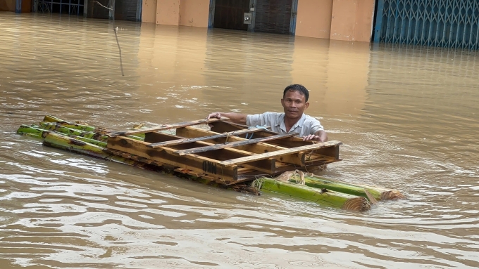 Một người dân ở phường Tuy Hòa, Đăk Lăk kết bè chuối lội nước lũ ra nhận đồ cứu trợ của các đội từ thiện, chiều 21/11. Ảnh: Lương Vĩnh Long Nhật