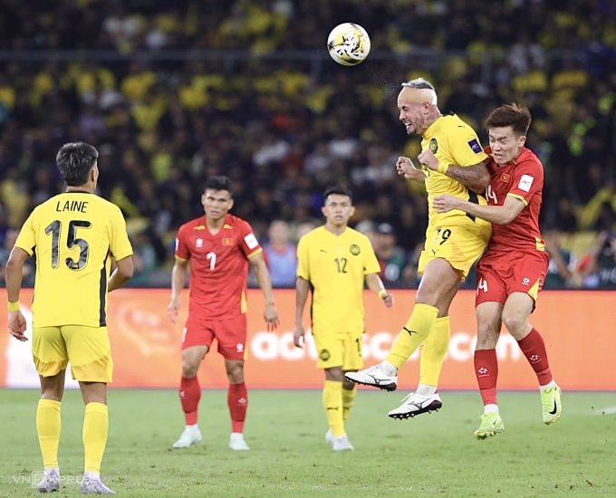 Nguyễn Hoàng Đức (áo đỏ phải) tranh chấp với tiền đạo Malaysia gốc Argentina Rodrigo Holgado trong trận Việt Nam thua Malaysia 0-4 ở lượt hai bảng F vòng loại cuối Asian Cup 2027, trên sân Bukit Jalil, Malaysia ngày 10/6/2025. Ảnh: Hai Tư