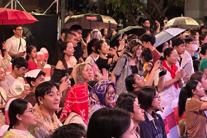 Khán giả ngồi chờ dưới mưa để gặp êkíp phim Mưa đỏ. Ảnh: Mai Nhật