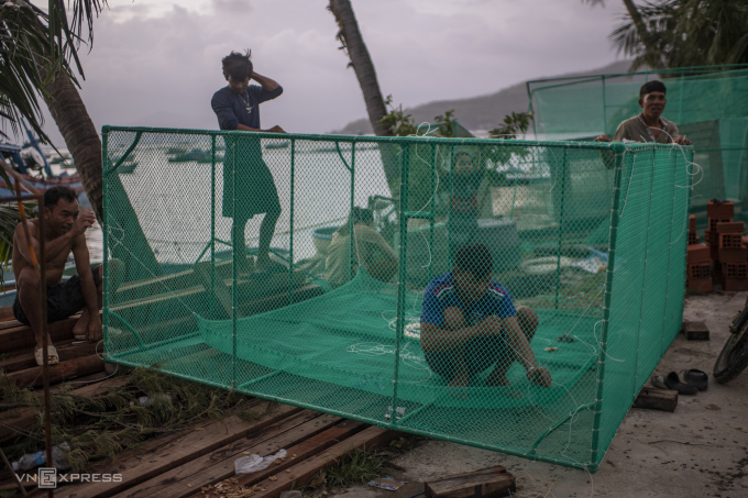 Anh Đoàn Văn Bi (áo xám) cùng bạn bè sửa lồng tôm hùm. Ảnh: Thanh Tùng